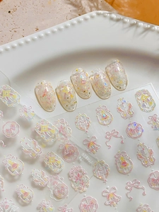 Detailed view of pink bow and star nail art stickers with iridescent shell effect finish