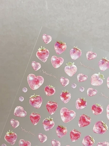 Dettaglio di adesivi per unghie con fragole rosa e cuori con scritte artistiche
