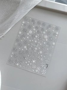 Macro shot of 3D embossed silver snowflake nail stickers with holographic shimmer details