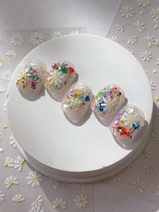 Detailed view of 3D white daisy nail stickers with pearls and floral petal designs