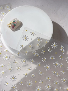 Macro view of 3D embossed white daisy nail stickers with yellow centers on clear sheets