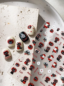 Detail showing cartoon black cat and red apple relief nail stickers on cream stone plate