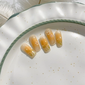 Faux ongles floraux avec dégradé ambre et motifs de tulipes peints à la main sur une assiette