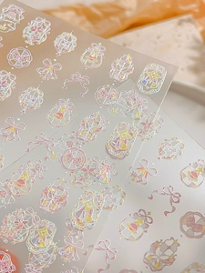 Close-up of holographic bow and star nail art stickers with iridescent shell finish
