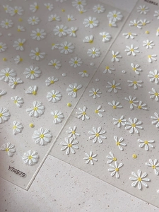 Macro shot of 3D embossed daisy nail stickers showing floral texture and white petals