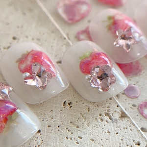 Unghie finte bianco traslucido con decorazioni fragole e strass a forma di fiorellino