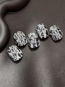 Dettaglio di 5 unghie finte corte quadrate con texture in marmo bianco e nero di lusso