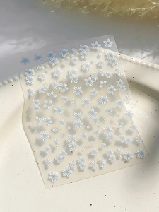 Detailed view of embossed white and blue floral nail art stickers on a textured plate