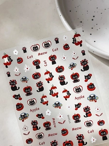 Close-up of cute black cat and red apple embossed nail art stickers with floral patterns