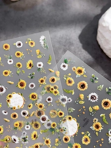 Detailed macro view of yellow sunflower and daisy nail stickers with green leaves on grey background