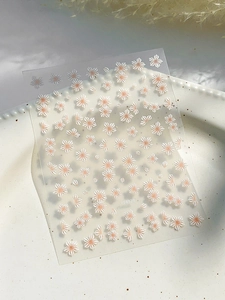 Detail of 3D embossed white floral nail stickers with orange centers on a clear backing