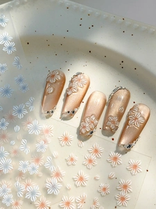 Macro shot of 3D embossed white daisy nail stickers with delicate matte texture and pearls