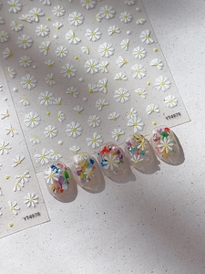 Close-up of embossed white daisy nail art stickers with 3D floral design effect