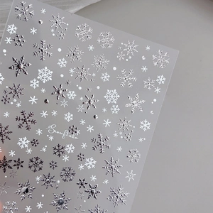 Self-adhesive silver and white snowflake nail art stickers with embossed metallic textures