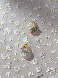 Detail of embossed white daisy nail stickers with 3D floral accents and pearl deco