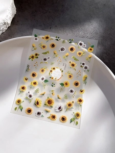 Detailed close-up of sunflower and daisy nail art stickers on a white ceramic plate