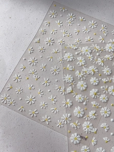 Close-up of 5D white daisy nail art stickers with embossed texture and yellow centers