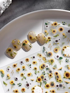 Macro detail of sunflower nail art stickers with golden butterfly accents and floral decals