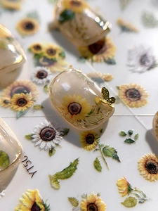 Macro detail of sunflower nail art stickers with golden 3D metal butterfly ornaments