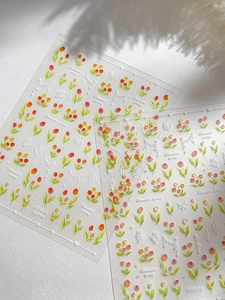 Détail macro de stickers 3D pour ongles aux motifs de tulipes et papillons en relief