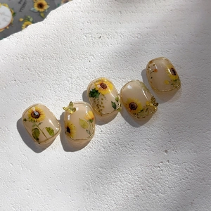 Cream sunflower press-on nails with elegant gold edges and 3D butterfly charms