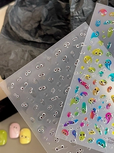 Macro shot of 3D slime eye nail stickers with transparent and gradient water droplet designs