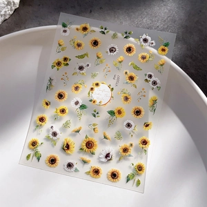 Flat sunflower nail stickers with yellow daisies and green leaves on a white bowl
