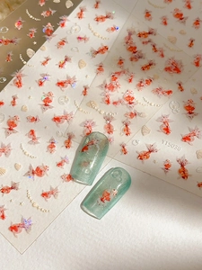Detail of goldfish and seashell nail art stickers with decorative pearl chain patterns