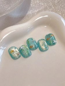 Macro detail of blue resin press-on nails with 3D starfish, goldfish, and glitter