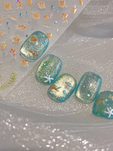 Macro view of blue cat-eye nails with 3D goldfish, sea grass, and starfishes decoration