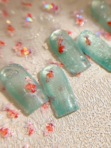 Macro detail of koi goldfish nail stickers with 3D water drops and shimmering blue finish