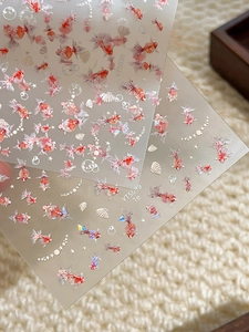 Detail of colorful koi fish nail art stickers with seashell and star patterns on matte sheet