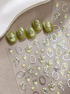 Détail de stickers à ongles muguet avec accents or et argent sur des ongles verts