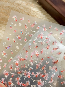 Macro detail of iridescent goldfish nail stickers with shells and laser shell pearl patterns