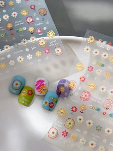 Detail view of colorful floral and smiley face nail art decals on colorful manicure samples