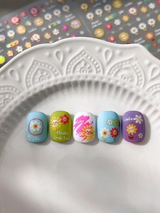 Detail of embossed sunflower nail stickers with hand-drawn daisy and smile patterns