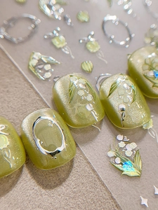 Vue macro de stickers ongles muguet avec lignes argentées gaufrées sur base de vert