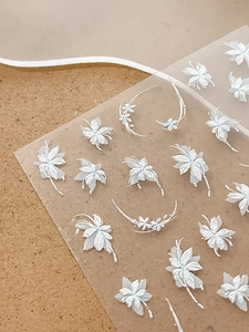 Macro detail of 5D embossed white floral nail art stickers with delicate 3D texture