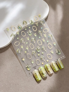 Vue détaillée des autocollants pour ongles muguet avec cadres dorés et motifs floraux verts
