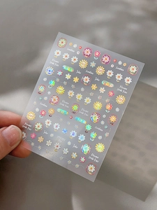 Detailed macro view of laser sunflower nail stickers with colorful smiley faces and text