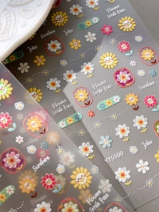 Detail of colorful sunflower nail stickers with smiley faces and artistic text patterns