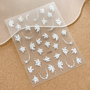 Close-up of white embossed floral nail stickers featuring delicate curved flower patterns