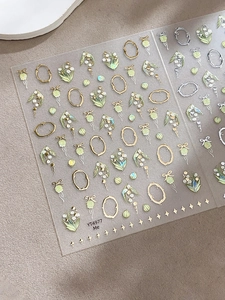 Détail des stickers ongles muguet avec cadres dorés et nœuds sur le modèle YT4977