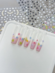 Detail of pink French style press-on nails with colorful 3D floral embossing and glossy finish