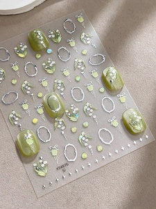 Gros plan détaillé de stickers à ongles muguet avec des accents floraux argentés gaufrés