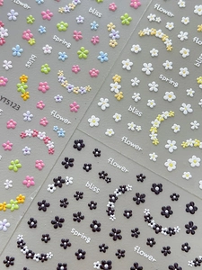 Macro shot of 3D embossed floral nail stickers with English text and matte texture