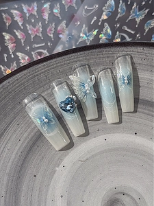 Detail of blue gradient long coffin fake nails with 3D butterfly and crystal accents