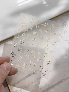 Détail d'autocollants nail art feuilles dorées avec motifs botaniques sur modèle YT5075