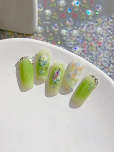 Detail of avocado green gradient press-on nails with 3D floral and butterfly accents