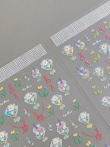 Macro detail of glossy 3D nail stickers featuring cute floral bouquets and red ribbons